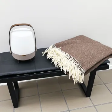 Bænk med hynde, uldplaid og højtalerlampe